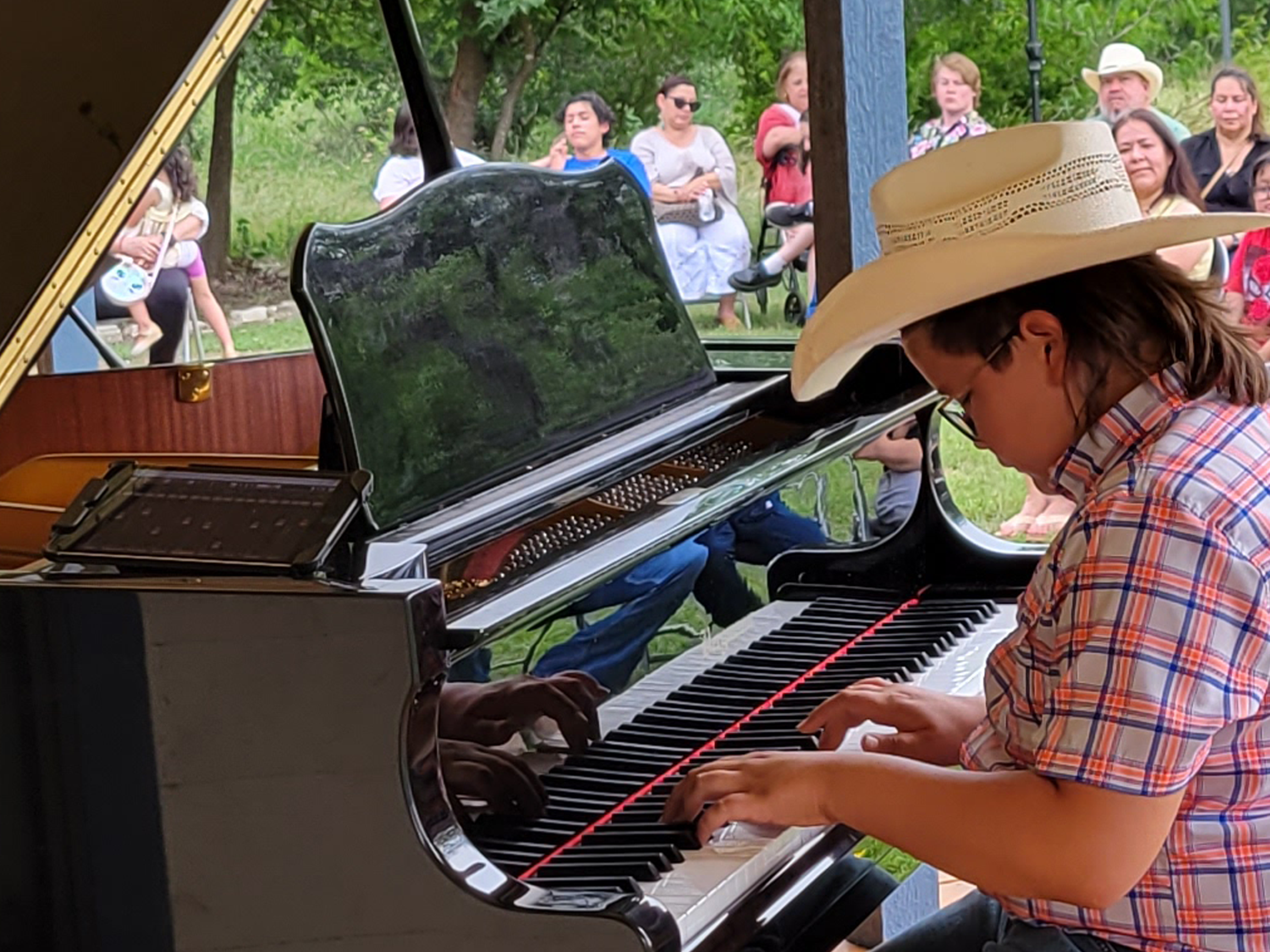 student in cowboy hat playing piano